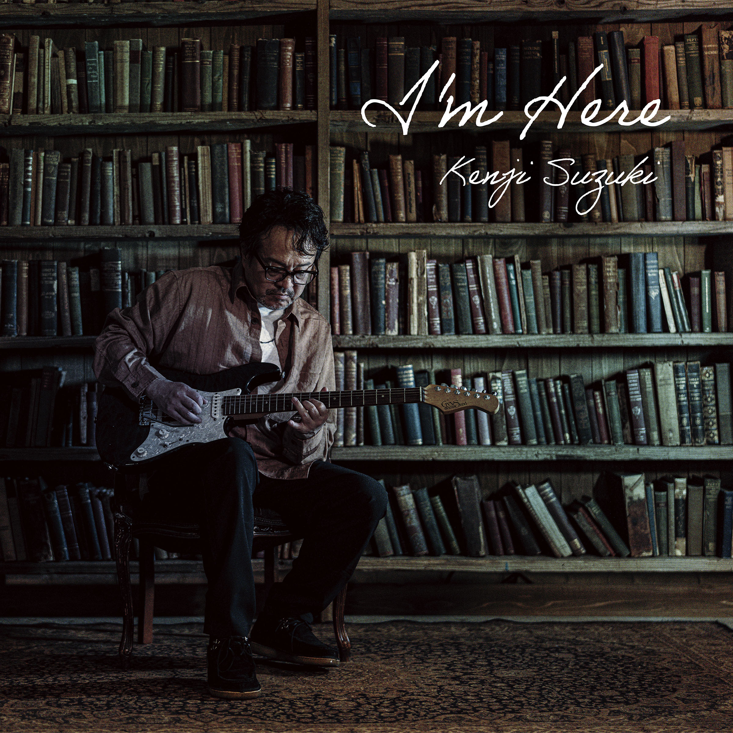 アルバム『I’m Here』のジャケット。ギターを弾く鈴木健治と本棚